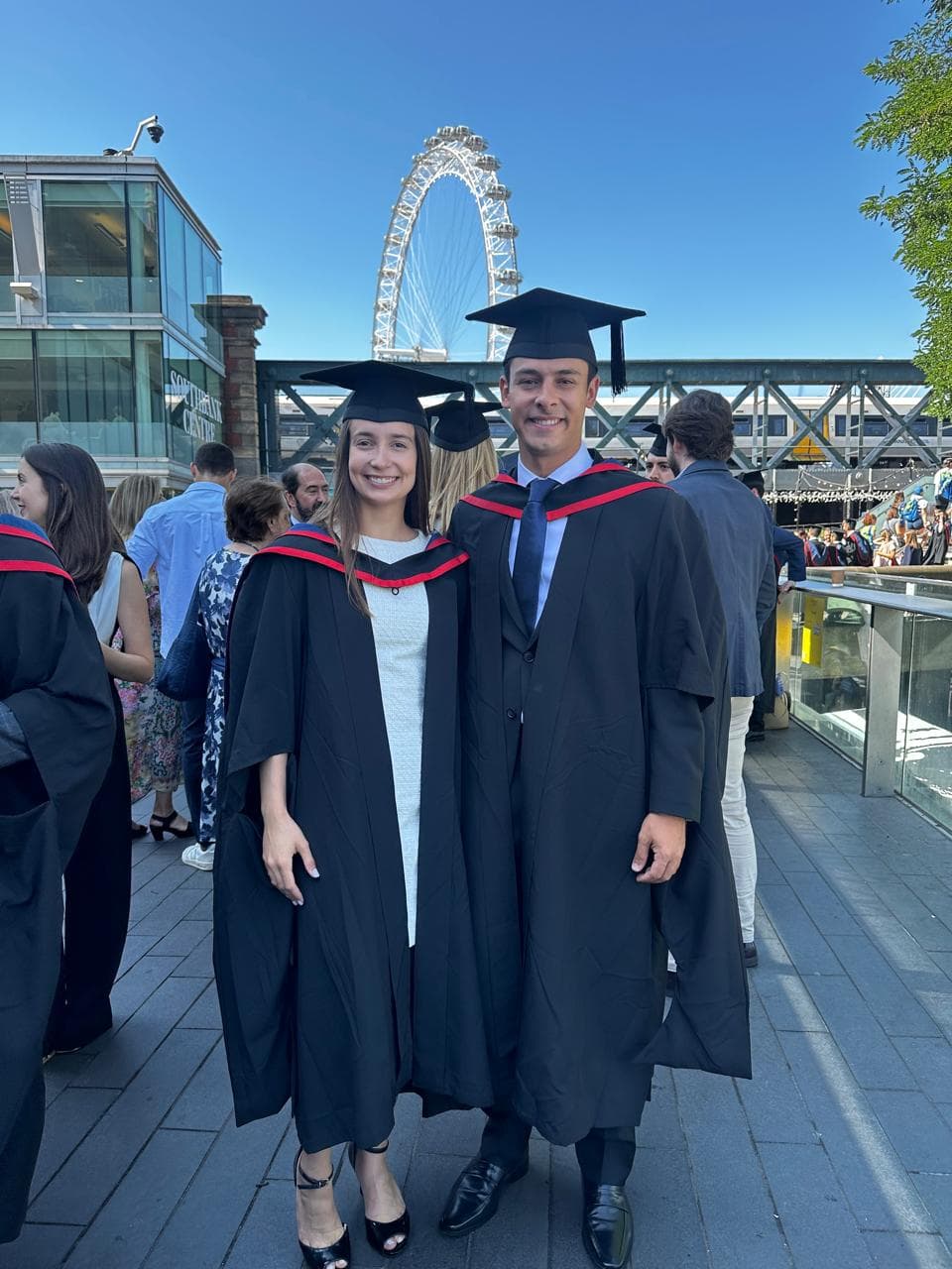 Luiza e João Pedro em becas de formatura, com a London Eye ao fundo